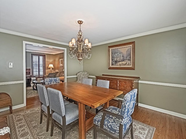 dining space with dark wood-type flooring, crown molding, and a notable chandelier