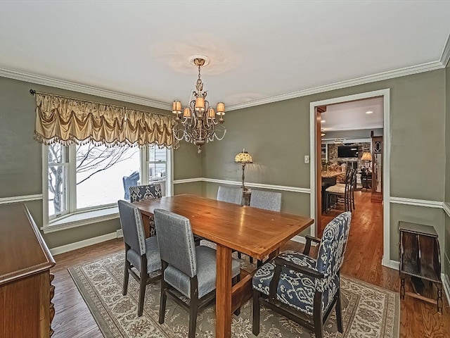 dining area featuring wood-type flooring, ornamental molding, and a chandelier