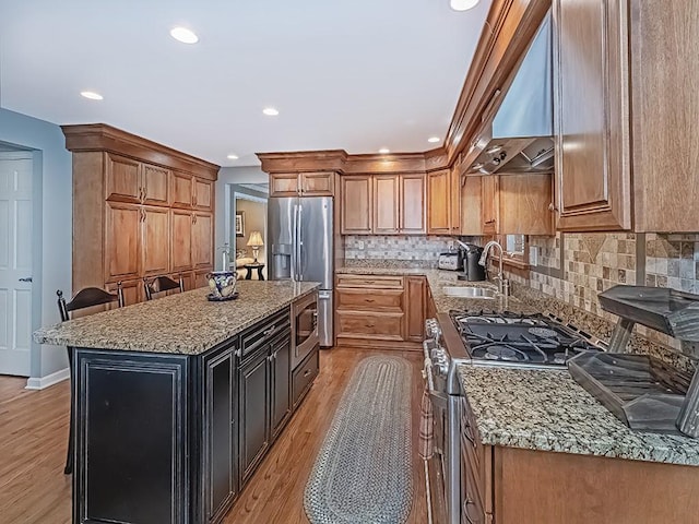 kitchen featuring light stone countertops, appliances with stainless steel finishes, a center island, and exhaust hood