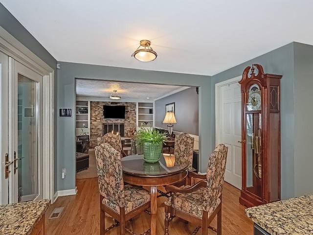 dining room featuring a fireplace, light hardwood / wood-style flooring, and built in features