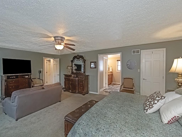 carpeted bedroom with ceiling fan, ensuite bathroom, and a textured ceiling