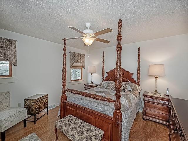 bedroom with ceiling fan, light hardwood / wood-style floors, and a textured ceiling