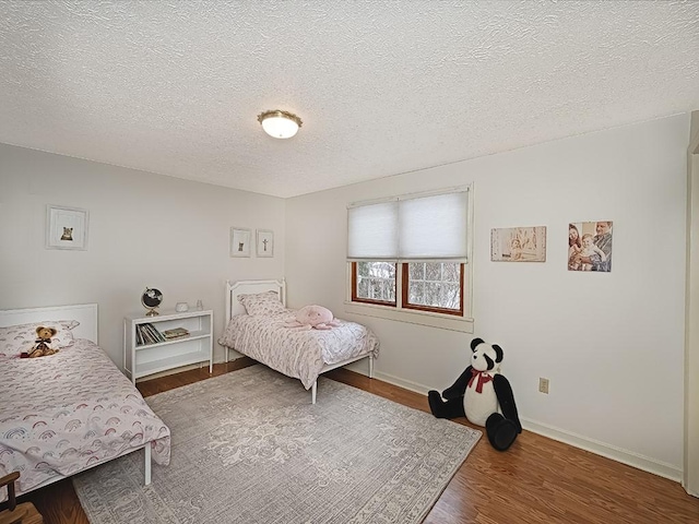 bedroom featuring a textured ceiling and dark hardwood / wood-style flooring