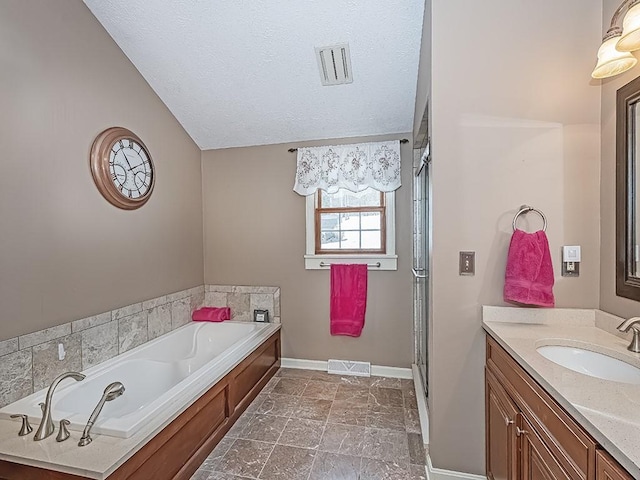 bathroom with vanity, vaulted ceiling, a textured ceiling, and separate shower and tub