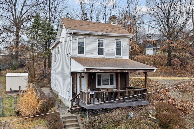 view of front facade featuring a shingled roof, a porch, fence, and a chimney