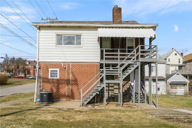 rear view of property featuring central AC and a lawn