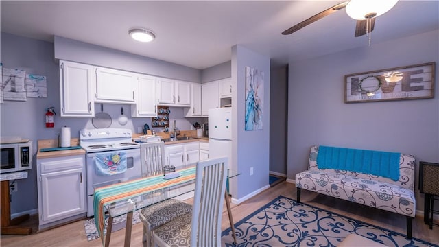 kitchen featuring white appliances, white cabinetry, light countertops, and a sink