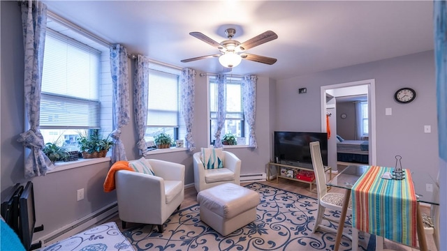 living area with baseboards, ceiling fan, a baseboard heating unit, and wood finished floors