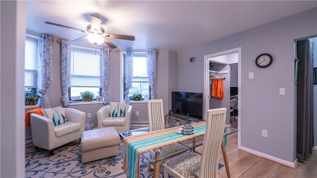 interior space with a baseboard heating unit, wood finished floors, a ceiling fan, and baseboards