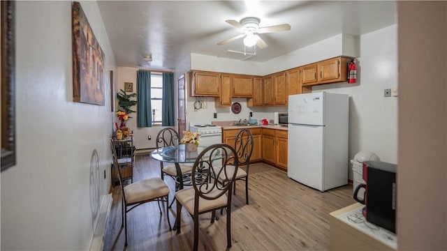 kitchen with white appliances, a sink, a ceiling fan, light countertops, and light wood finished floors