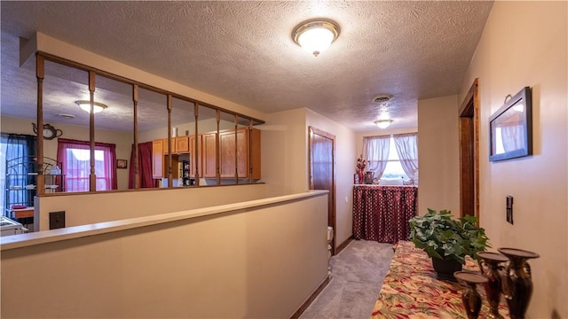 corridor featuring light colored carpet, visible vents, and a textured ceiling