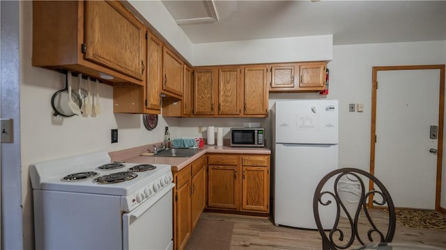 kitchen with light countertops, white appliances, a sink, and brown cabinets