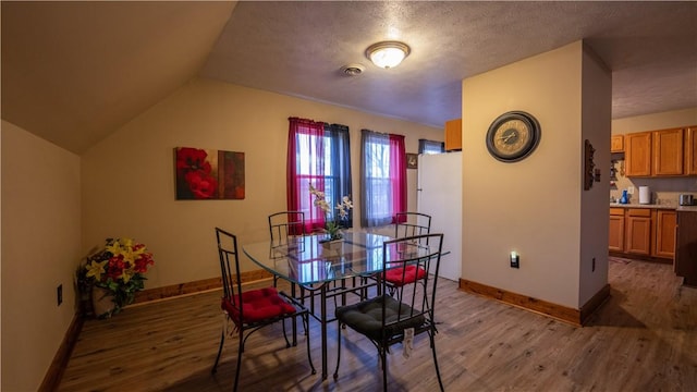 dining room featuring lofted ceiling, wood finished floors, visible vents, and baseboards