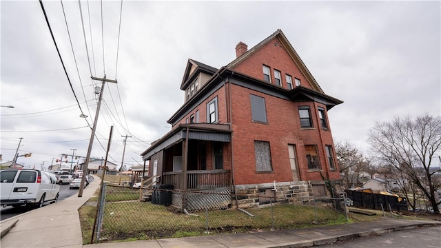 view of property exterior with a fenced front yard, a chimney, and brick siding