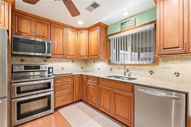 kitchen with stainless steel appliances, tasteful backsplash, light stone countertops, and sink