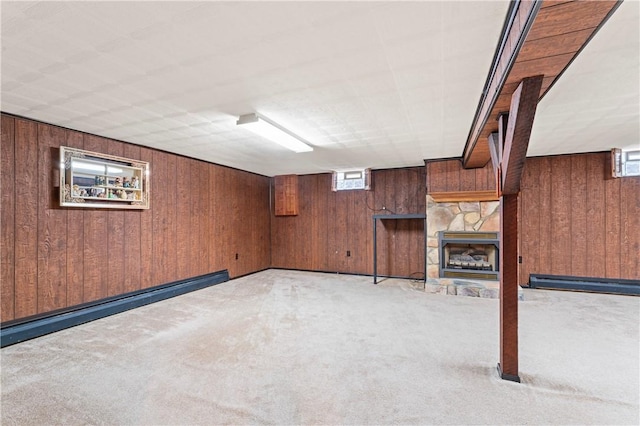 basement featuring a baseboard heating unit, light colored carpet, a fireplace, and wood walls