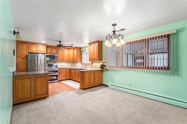 kitchen with appliances with stainless steel finishes, decorative light fixtures, a baseboard radiator, sink, and light colored carpet