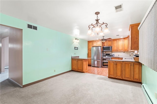 kitchen featuring pendant lighting, sink, appliances with stainless steel finishes, a baseboard heating unit, and kitchen peninsula