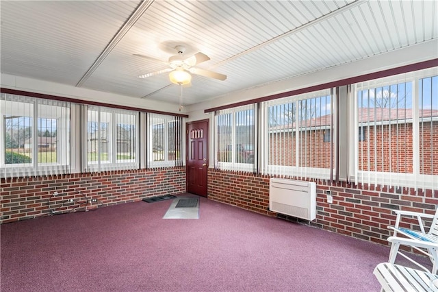 unfurnished sunroom with plenty of natural light, a wall mounted AC, and ceiling fan