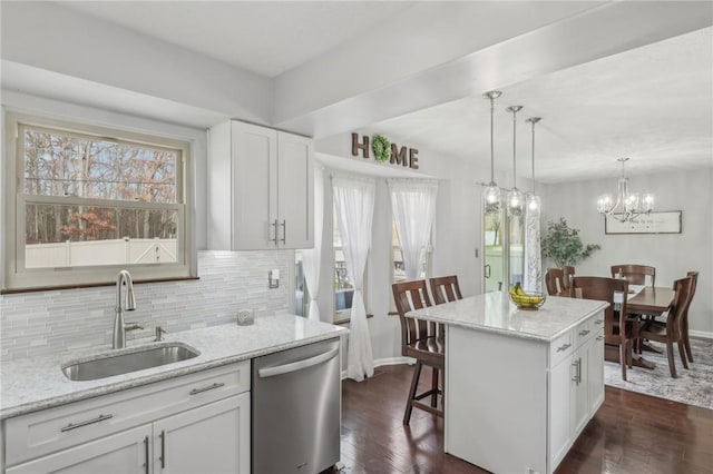 kitchen with sink, a breakfast bar, dishwasher, a center island, and white cabinets