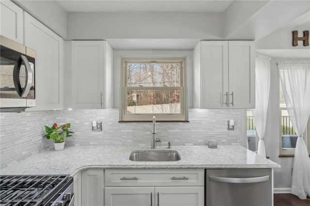 kitchen featuring white cabinetry, appliances with stainless steel finishes, sink, and light stone counters