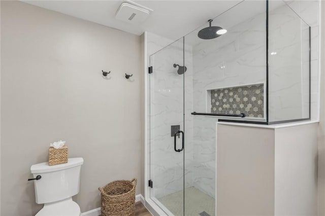 bathroom featuring a shower with door and toilet