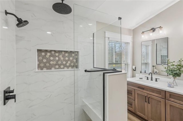 bathroom with a tile shower and vanity