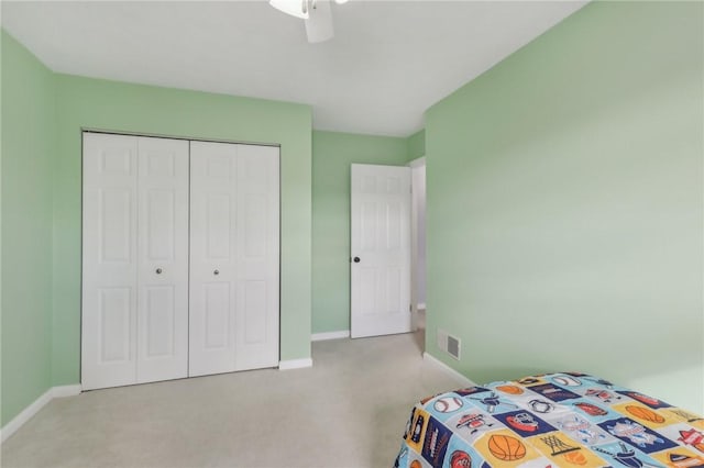 bedroom with ceiling fan, light colored carpet, and a closet