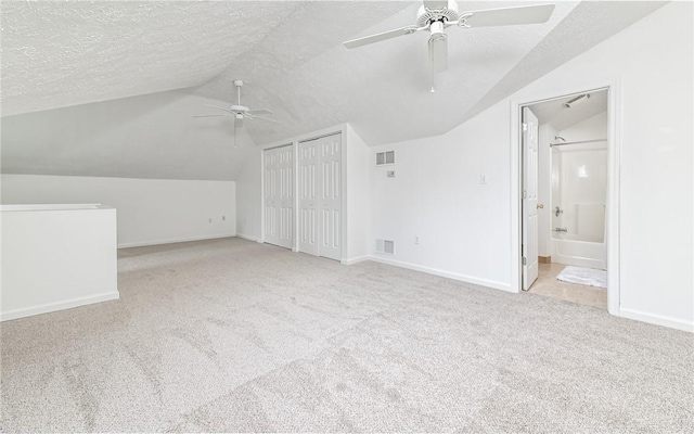 bonus room with light carpet, ceiling fan, vaulted ceiling, and a textured ceiling