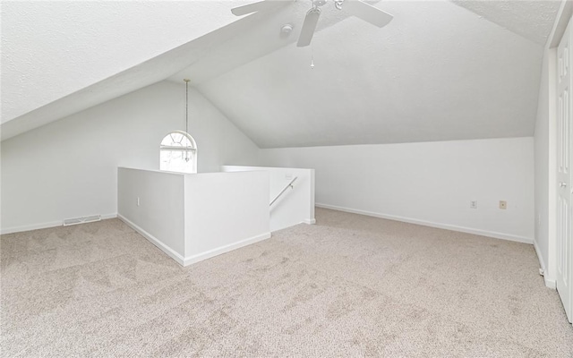 bonus room with ceiling fan, light colored carpet, lofted ceiling, and a textured ceiling