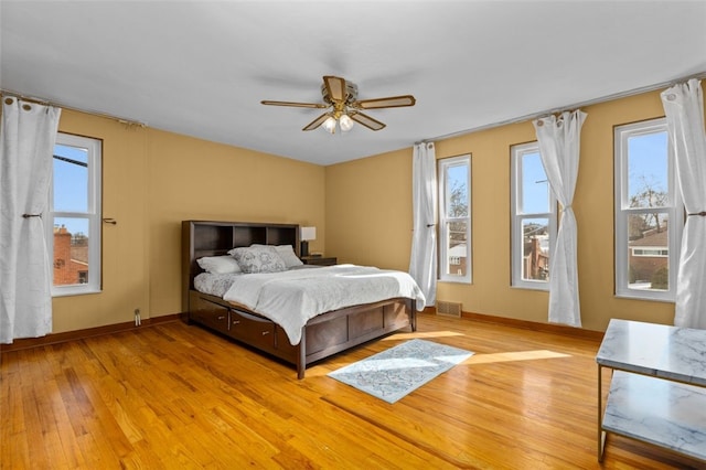 bedroom featuring visible vents, multiple windows, baseboards, and light wood-style floors