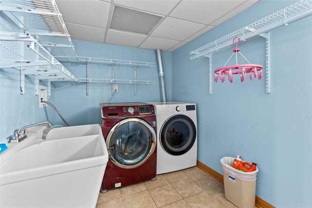 clothes washing area with light tile patterned floors, baseboards, laundry area, a sink, and independent washer and dryer