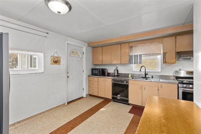 kitchen featuring black appliances, light brown cabinets, a sink, stainless steel countertops, and under cabinet range hood