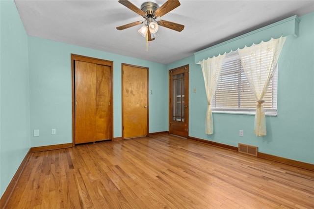 unfurnished bedroom featuring light wood finished floors, visible vents, two closets, and baseboards