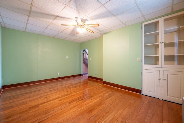 spare room with a drop ceiling, light hardwood / wood-style flooring, and ceiling fan