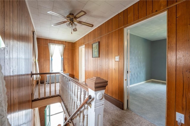 hall with light colored carpet and wooden walls