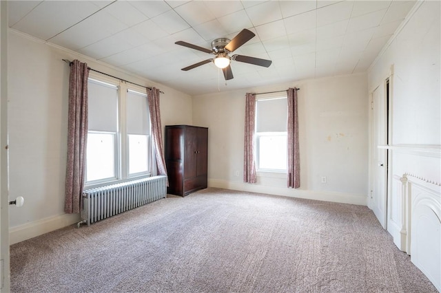 unfurnished room with ornamental molding, radiator heating unit, light colored carpet, and ceiling fan