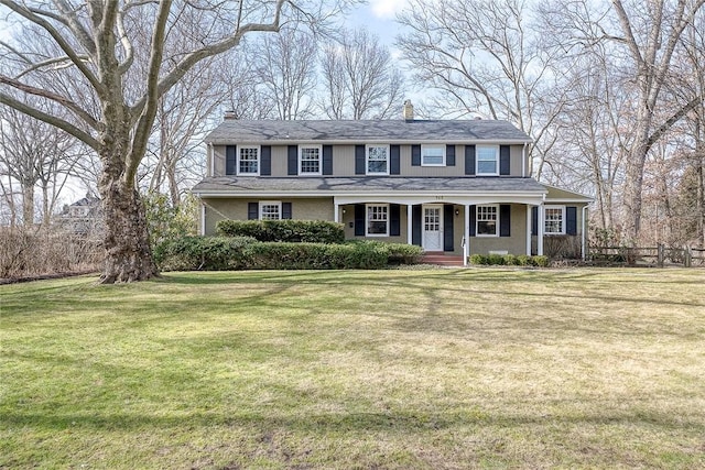 colonial inspired home featuring covered porch and a front lawn