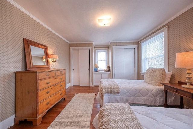 bedroom with hardwood / wood-style flooring, crown molding, and multiple closets