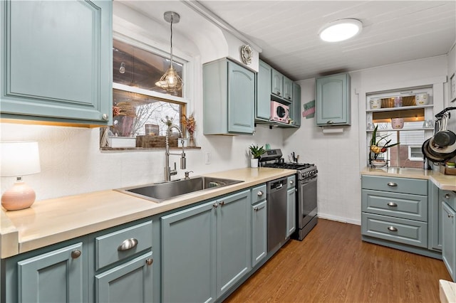 kitchen featuring hanging light fixtures, appliances with stainless steel finishes, sink, and light hardwood / wood-style floors