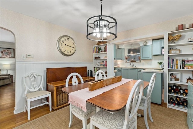 dining space with an inviting chandelier, sink, and wood-type flooring