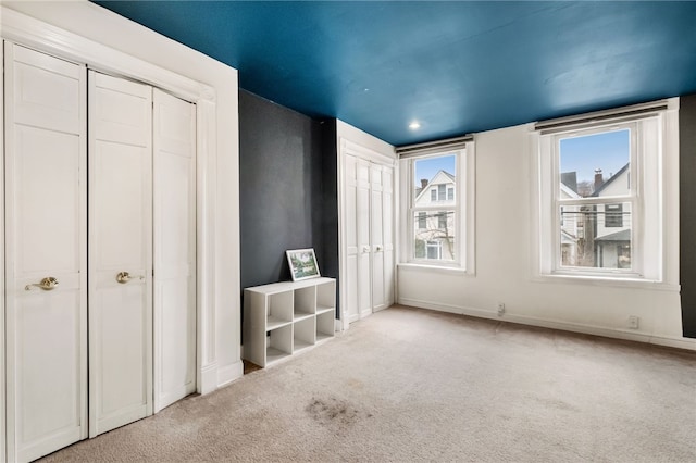 unfurnished bedroom featuring two closets and light carpet