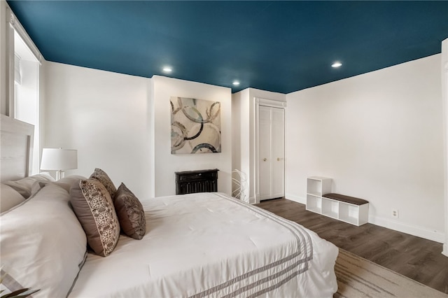 bedroom with dark hardwood / wood-style floors and a closet