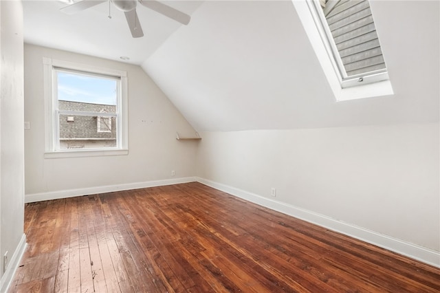 additional living space with hardwood / wood-style flooring, vaulted ceiling with skylight, and ceiling fan