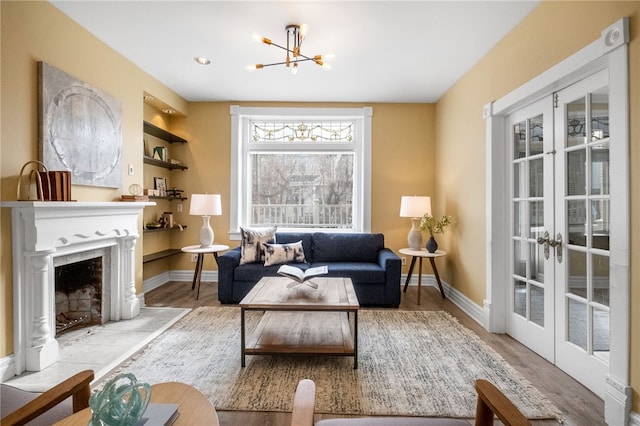 living room with french doors, a chandelier, built in features, and light wood-type flooring