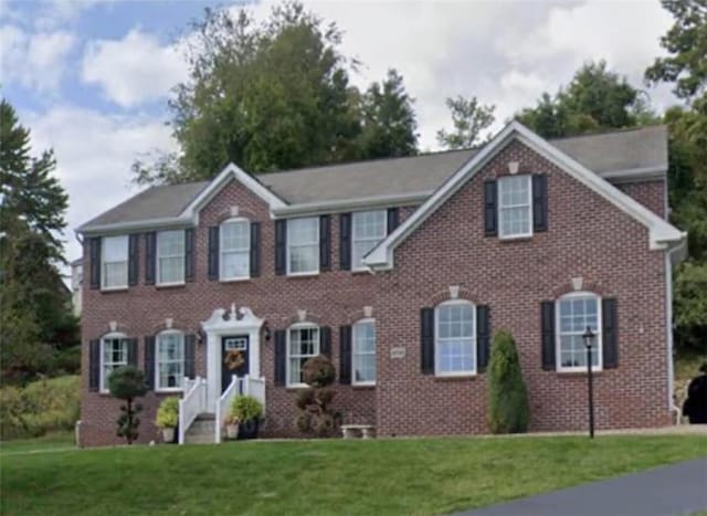 colonial home with a front yard and brick siding