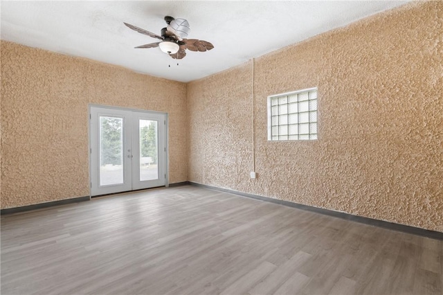 empty room featuring french doors, ceiling fan, and hardwood / wood-style flooring