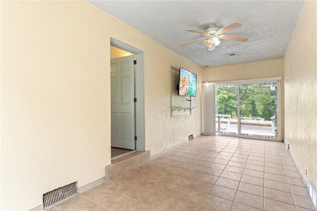 tiled empty room featuring ceiling fan and a textured ceiling