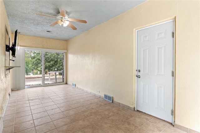 empty room featuring light tile patterned floors, a textured ceiling, and ceiling fan