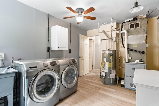 washroom with washing machine and clothes dryer, gas water heater, cabinets, light hardwood / wood-style flooring, and ceiling fan